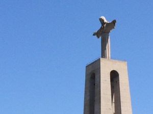 A large statue of Jesus overlooks the port of Belem arms outstretched protectively